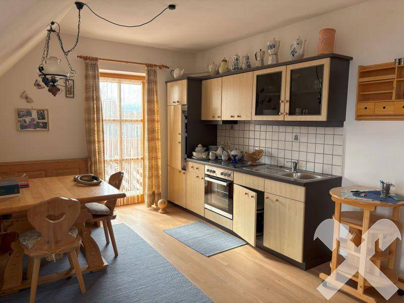 Kleine Wohnküche mit Essbereich, hellen Holzschränken und Laminatboden.