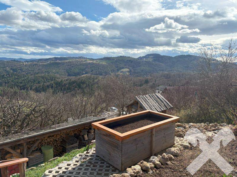 Erhöhtes Hochbeet im Gartenbereich mit Steineinfassung und Panoramablick auf die grüne Umgebung.