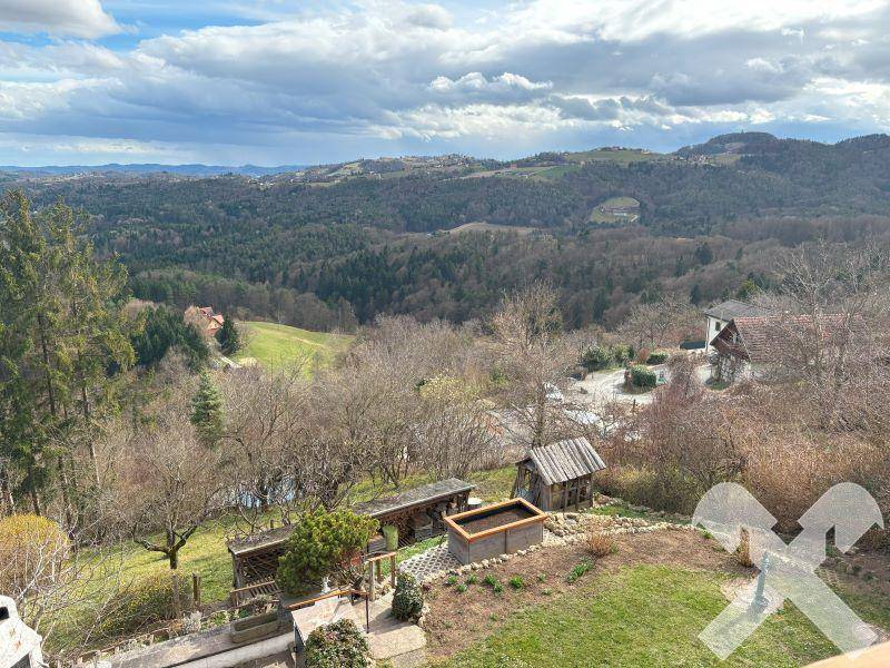 Weitläufiger Gartenbereich mit Rasenfläche und einem beeindruckenden Blick über die bewaldete Hügellandschaft.