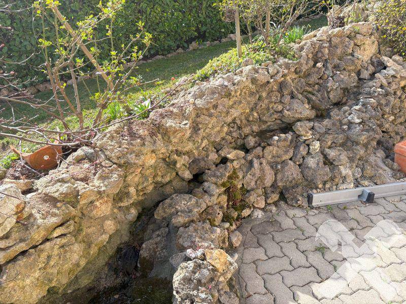 Natürliche Felsformation und Steingarten im Außenbereich mit gepflastertem Weg.