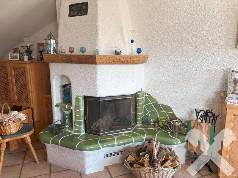 Traditioneller Kachelofen mit grünen Akzenten und Holzscheiten, der eine gemütliche Atmosphäre schafft.