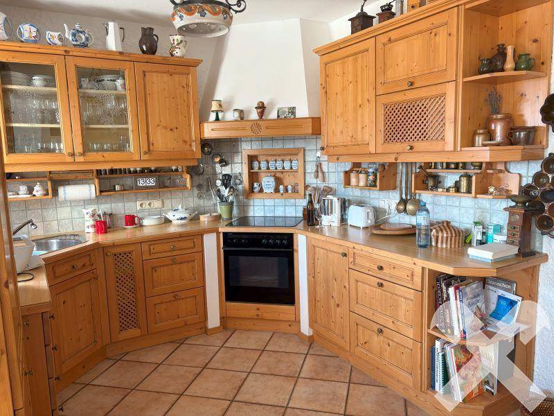 Gemütliche Küche im Landhausstil mit massiven Holzschränken, Fliesenboden und integrierten Geräten.