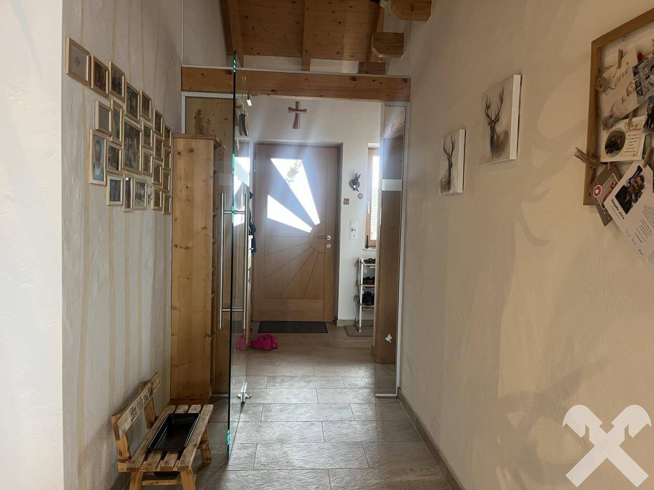 Eingangsbereich mit Holztür, Fliesenboden und rustikalen Holzelementen.