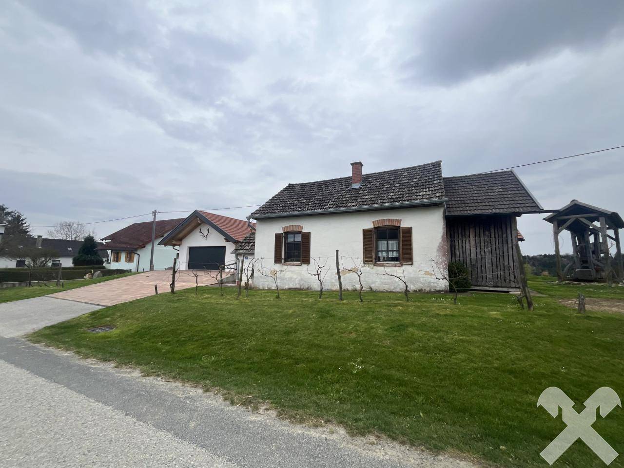 Traditionelles altes Haus mit Holzfensterläden und gepflegtem Vorgarten an der Straße.