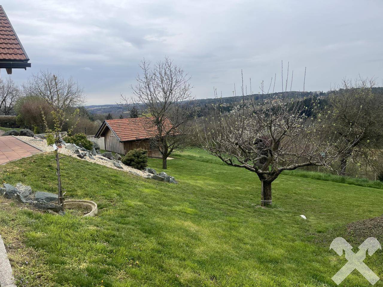 Weitläufiger Gartenbereich mit Rasenfläche, Obstbäumen und einem kleinen Gartenhaus.