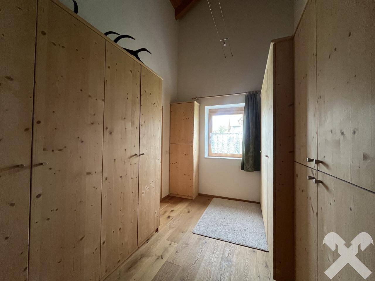 Geräumiger Ankleidebereich mit maßgefertigten Holzschränken und Fenster.