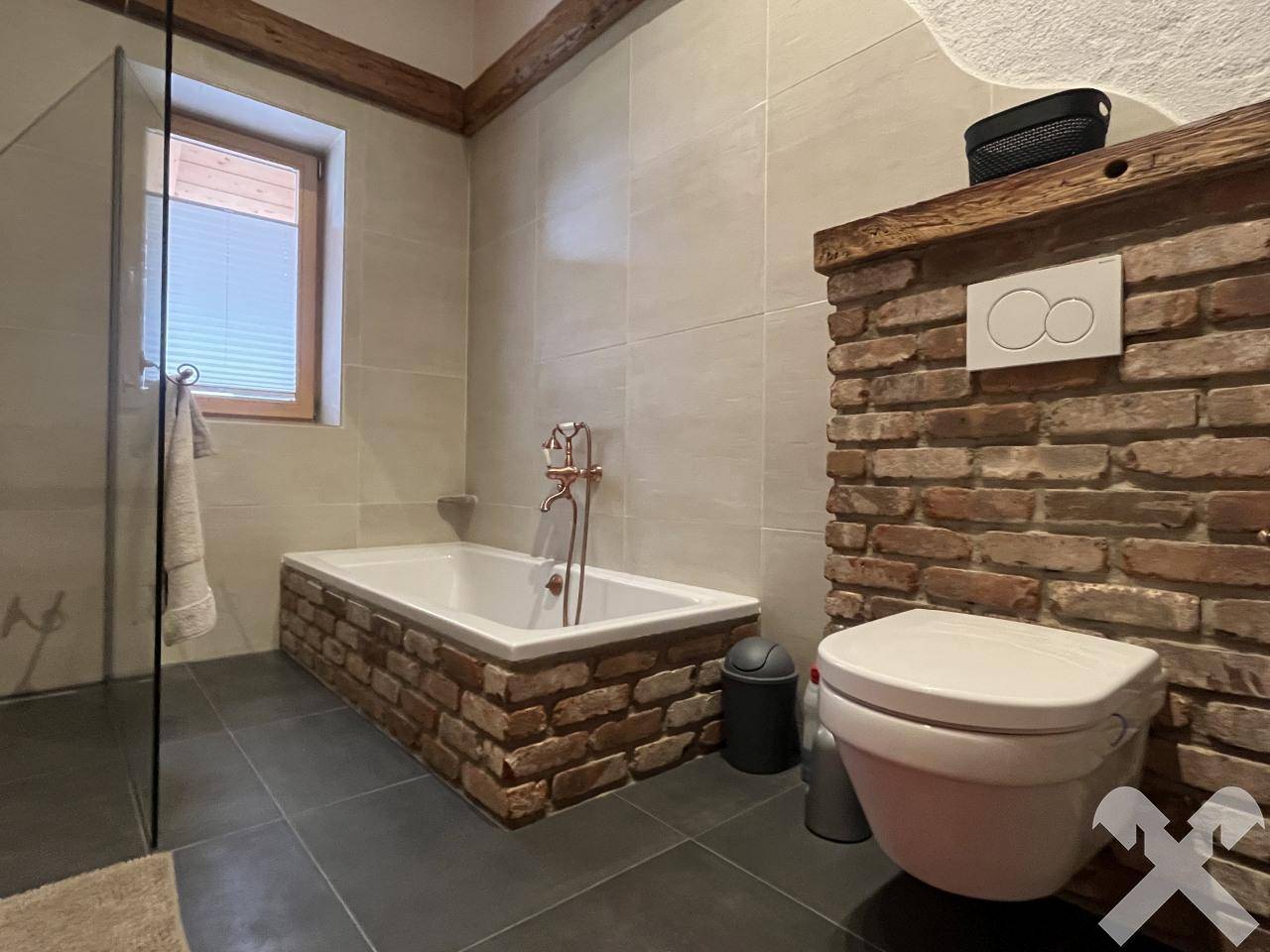 Badezimmer mit Ziegelwand, Badewanne, Dusche und wandhängendem WC.
