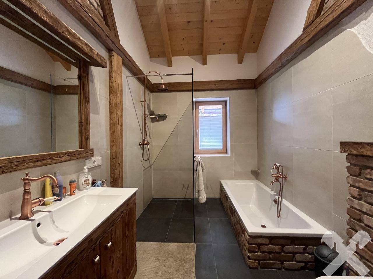 Modernes Badezimmer mit Doppelwaschbecken, begehbarer Dusche und Badewanne mit Ziegelverkleidung.