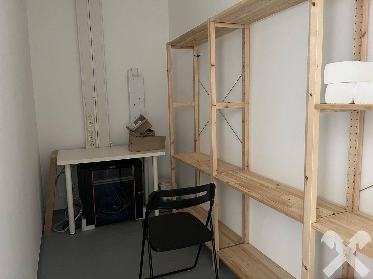 Kleiner Abstellraum oder Serverraum mit Holzregalen, einem Schreibtisch und technischer Ausstattung.