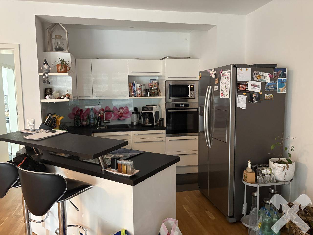 Moderne Küche mit weißen Schränken, schwarzen Arbeitsplatten und einer praktischen Kücheninsel mit Barhockern.