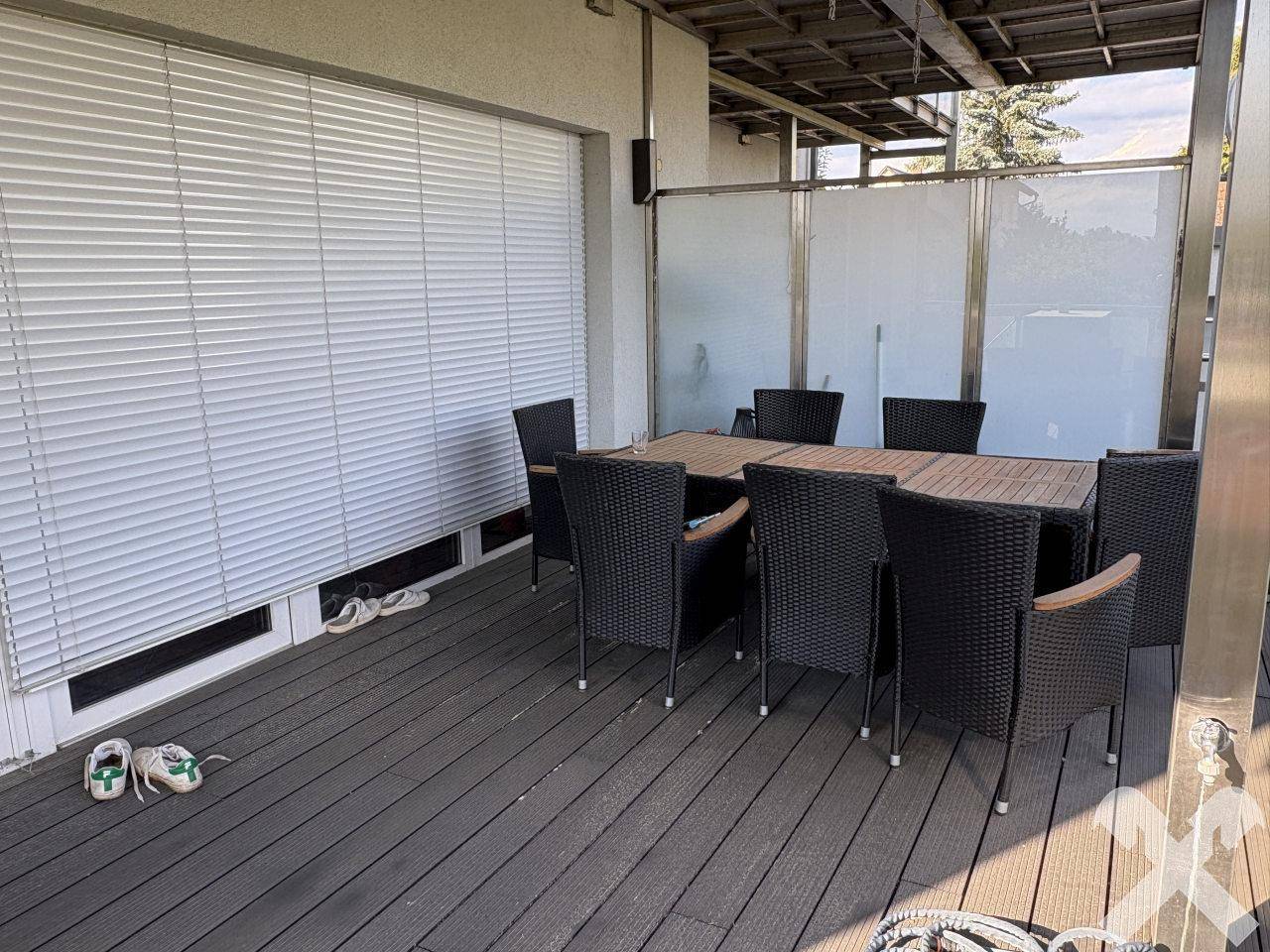 Geräumige Terrasse mit Holzboden, großem Esstisch und Stühlen, ideal für Mahlzeiten im Freien.