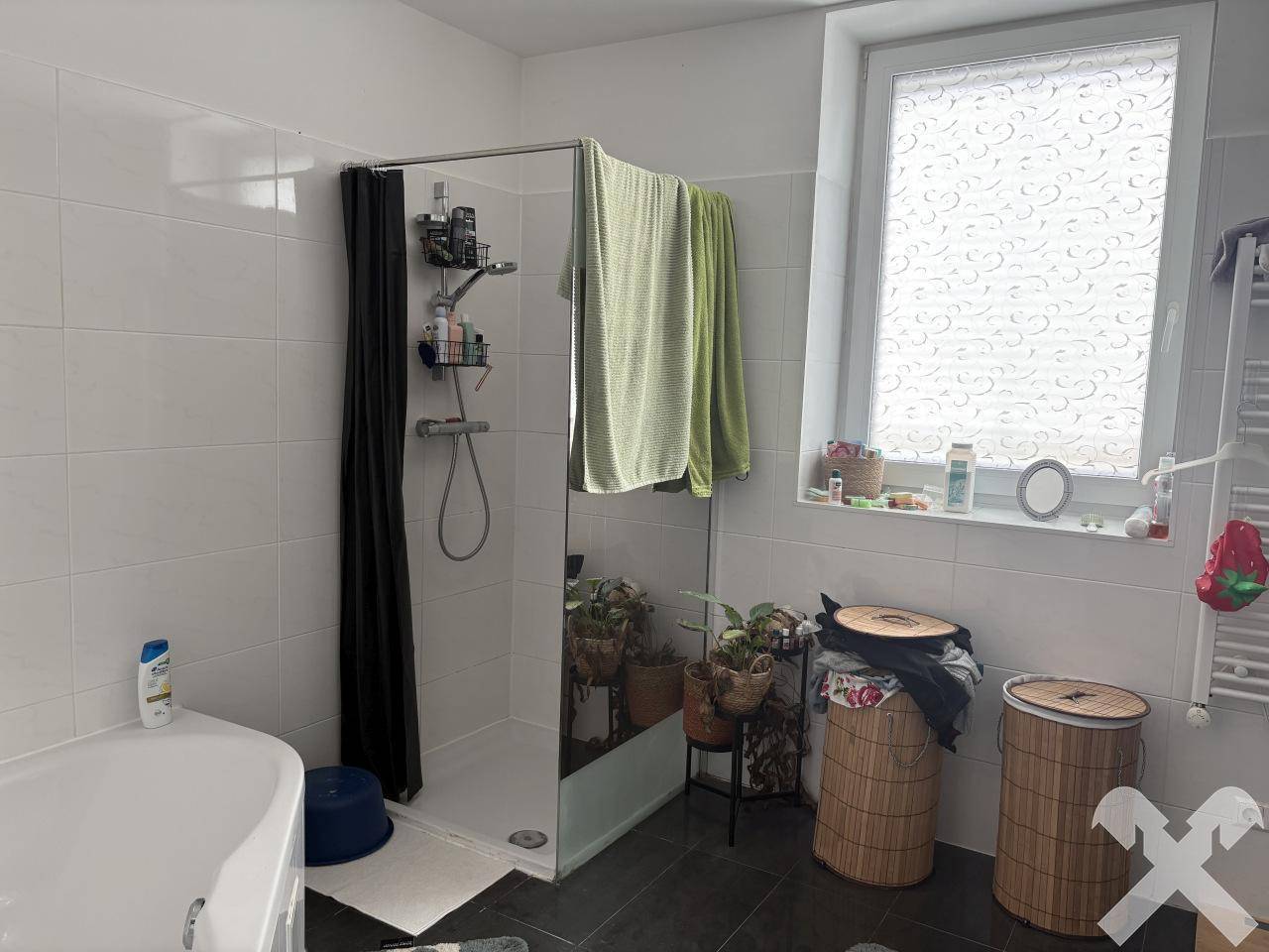 Badezimmer mit Duschkabine, Eckbadewanne und einem Fenster, ausgestattet mit weißen Fliesen.