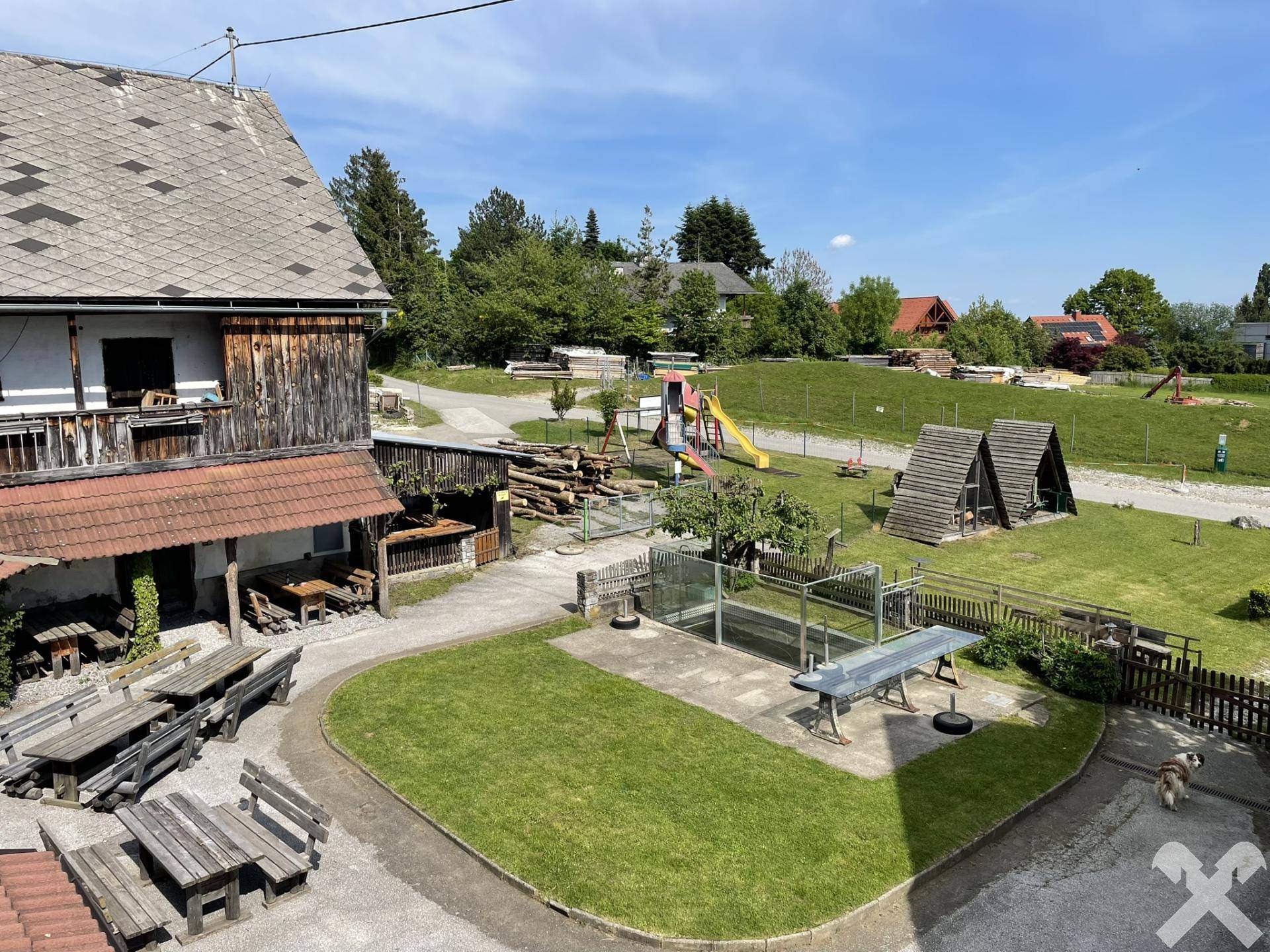 Großer Außenbereich mit Kinderspielplatz, Tischtennisplatte und rustikalen Sitzgelegenheiten.