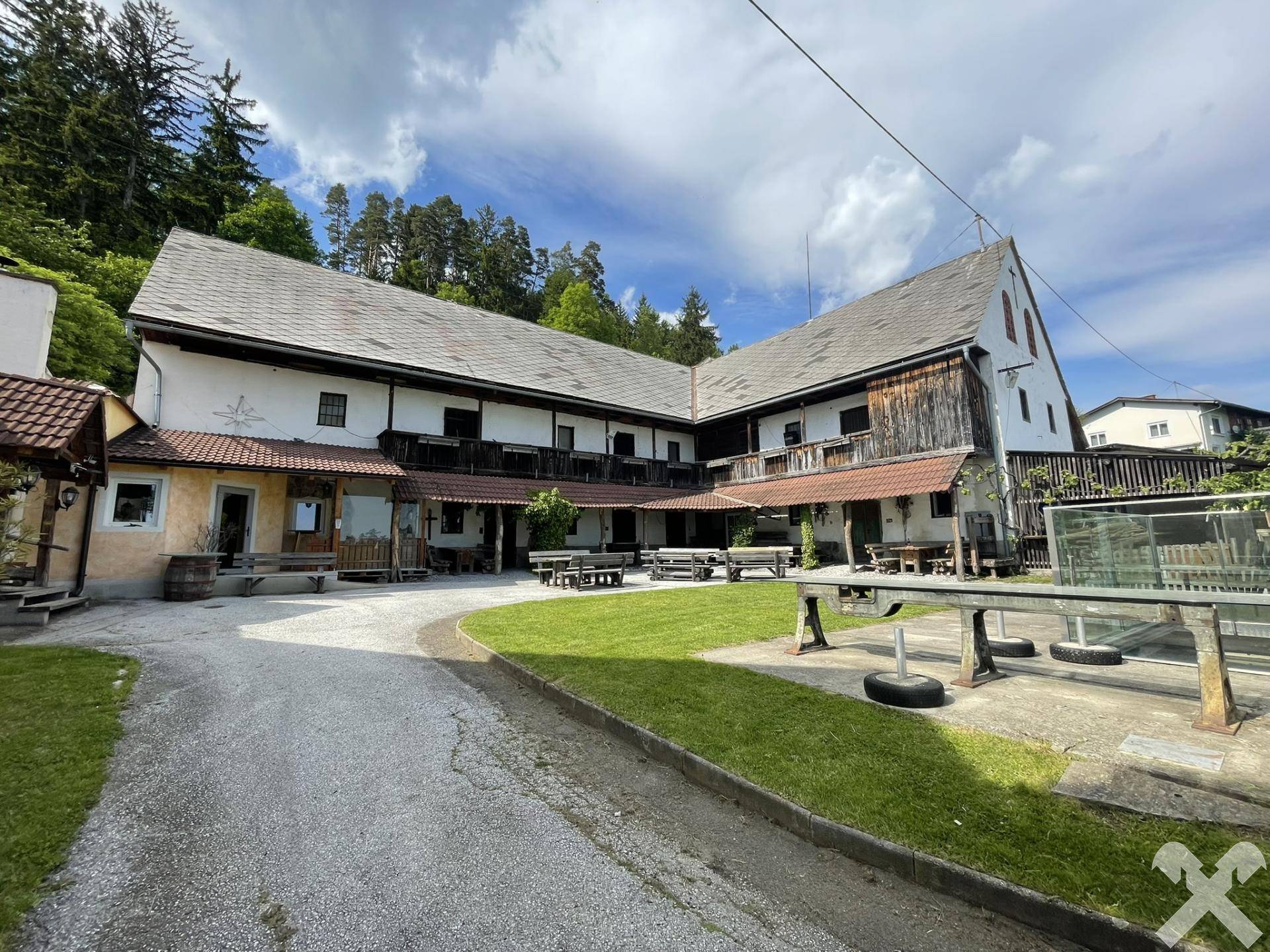 Traditioneller Gebäudekomplex mit großem Innenhof, umgeben von Wald und ländlicher Architektur.