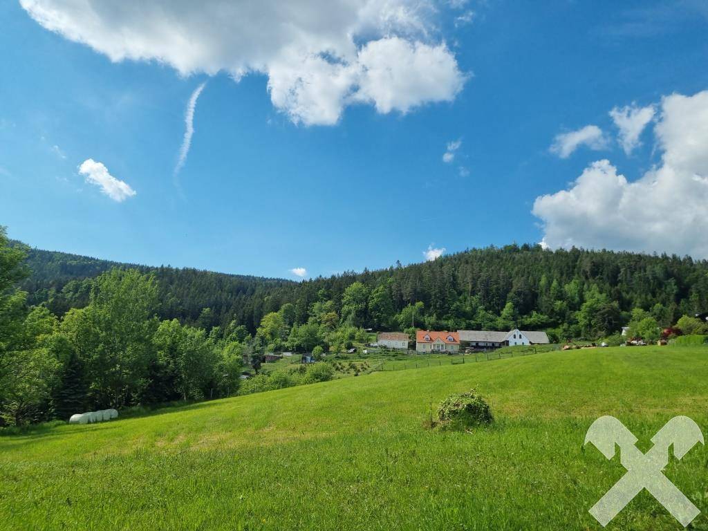 Weitläufige grüne Landschaft mit sanften Hügeln, Wäldern und einem weiten Blick in die Ferne.