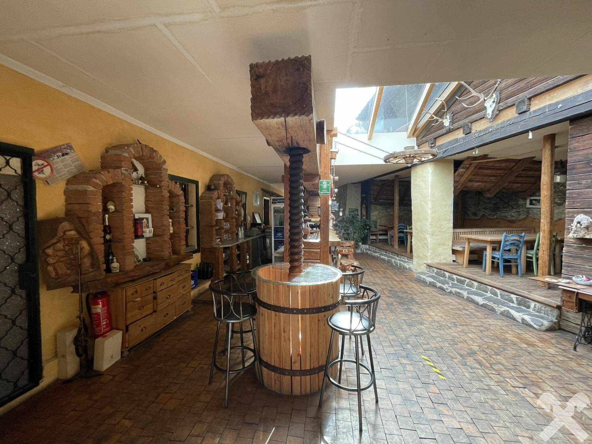 Rustikaler Barbereich mit Holzelementen, Ziegelbögen und einer traditionellen Weinpresse als Dekoration.