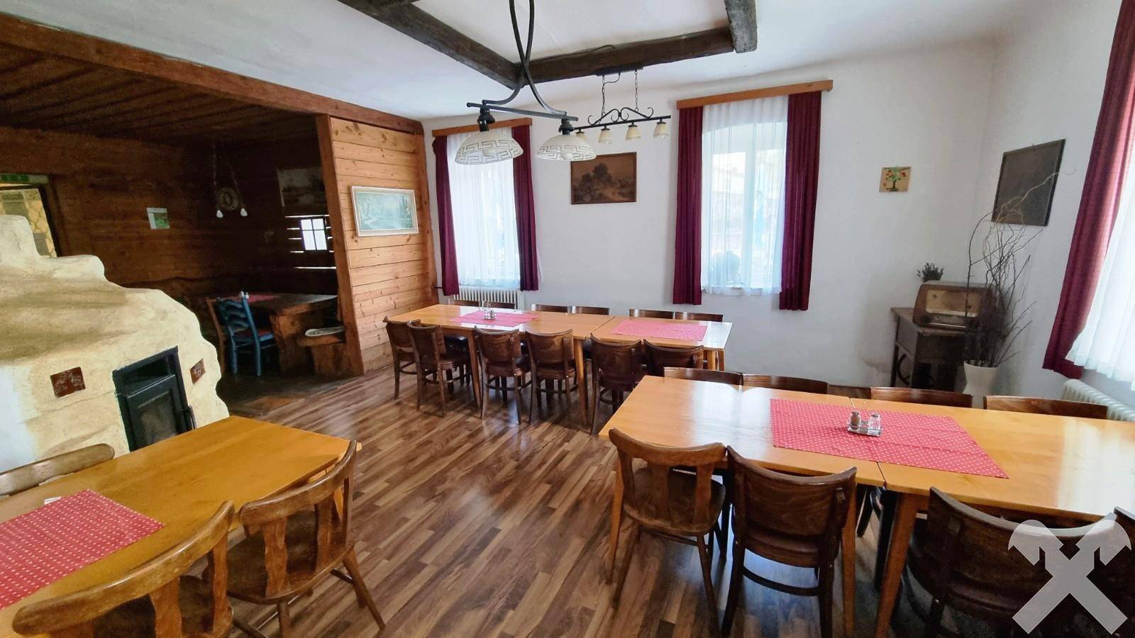 Rustikaler Essbereich mit Holztischen, Bänken und einem traditionellen Kachelofen.