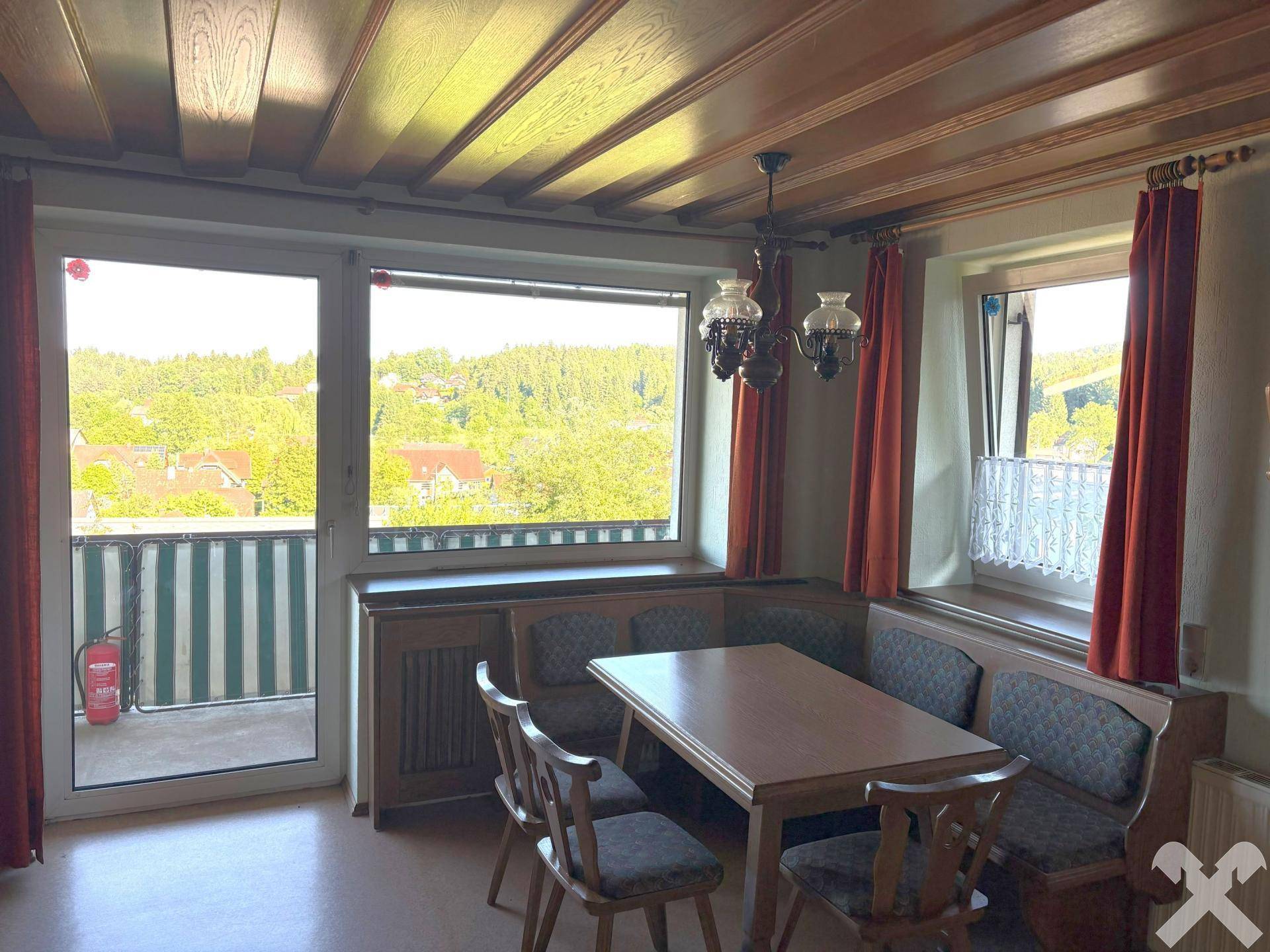 Gemütlicher Essbereich mit Holztäfelung, traditionellen Möbeln und Zugang zum Balkon.