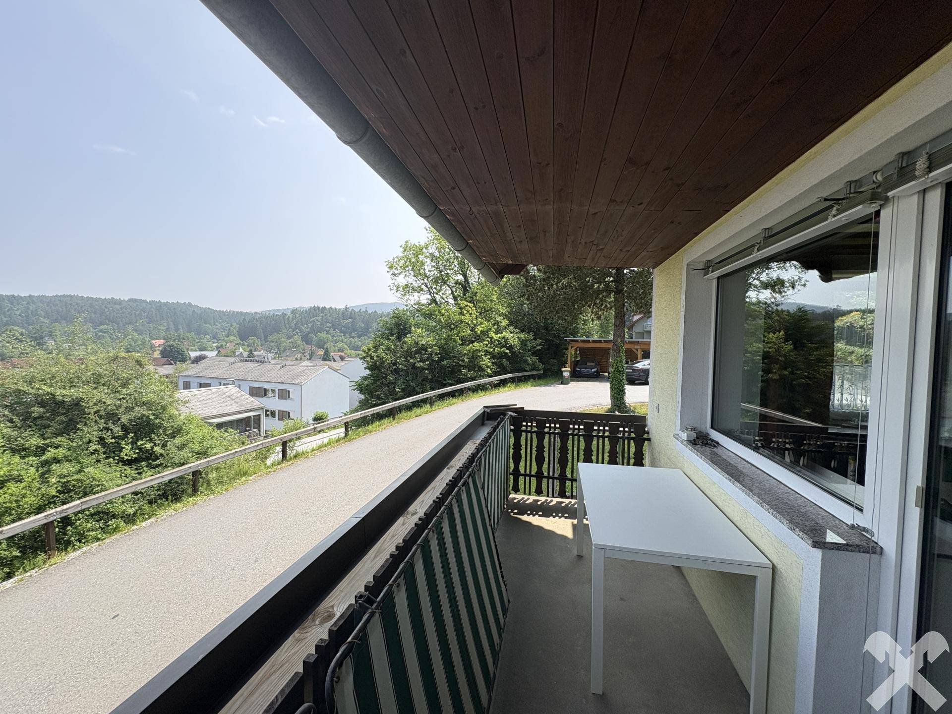 Langer Balkon mit kleinem Tisch und weitem Blick über die grüne Landschaft.