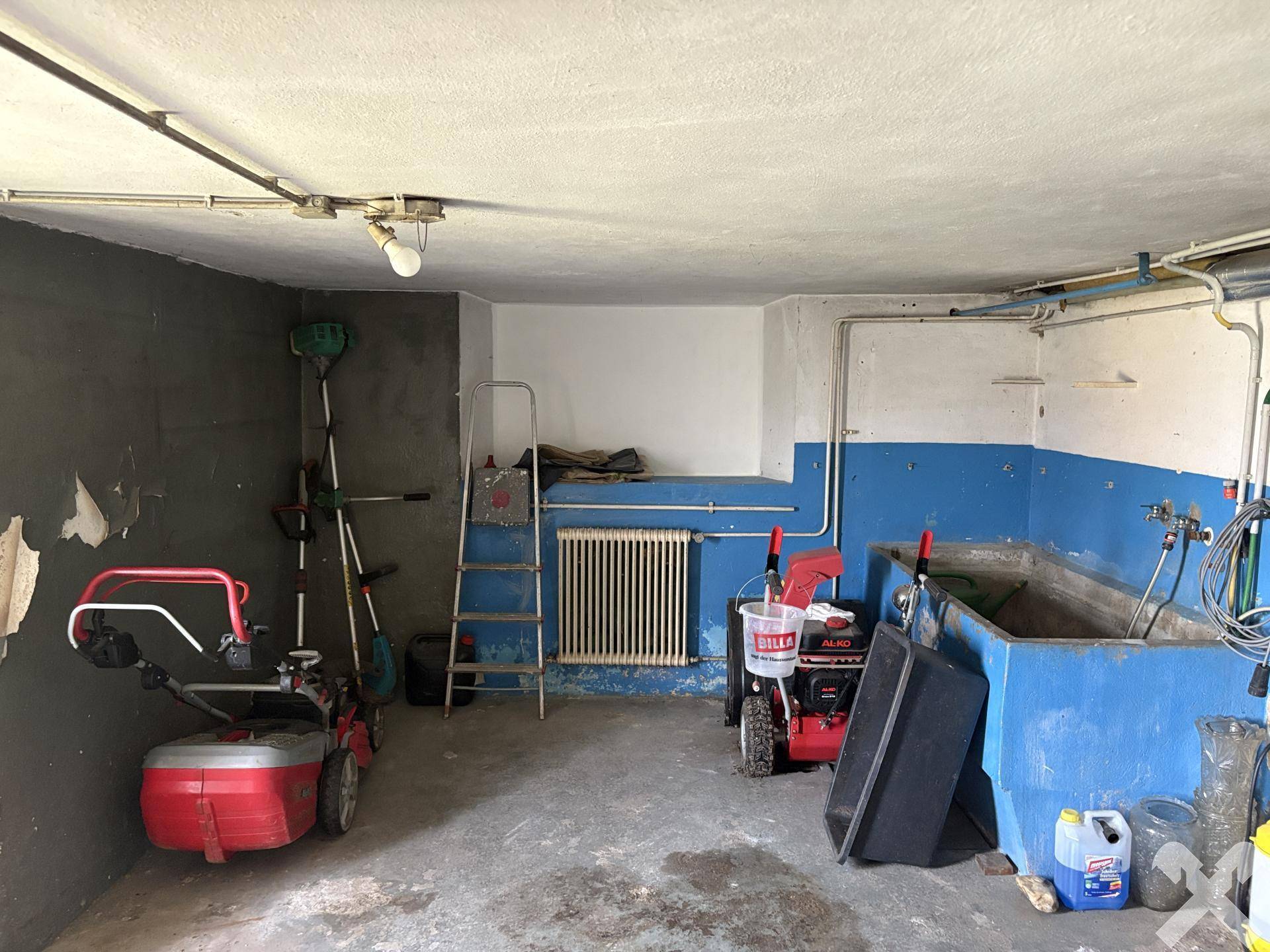 Geräumiger Hauswirtschaftsraum im Keller mit Waschbecken und verschiedenen Geräten.