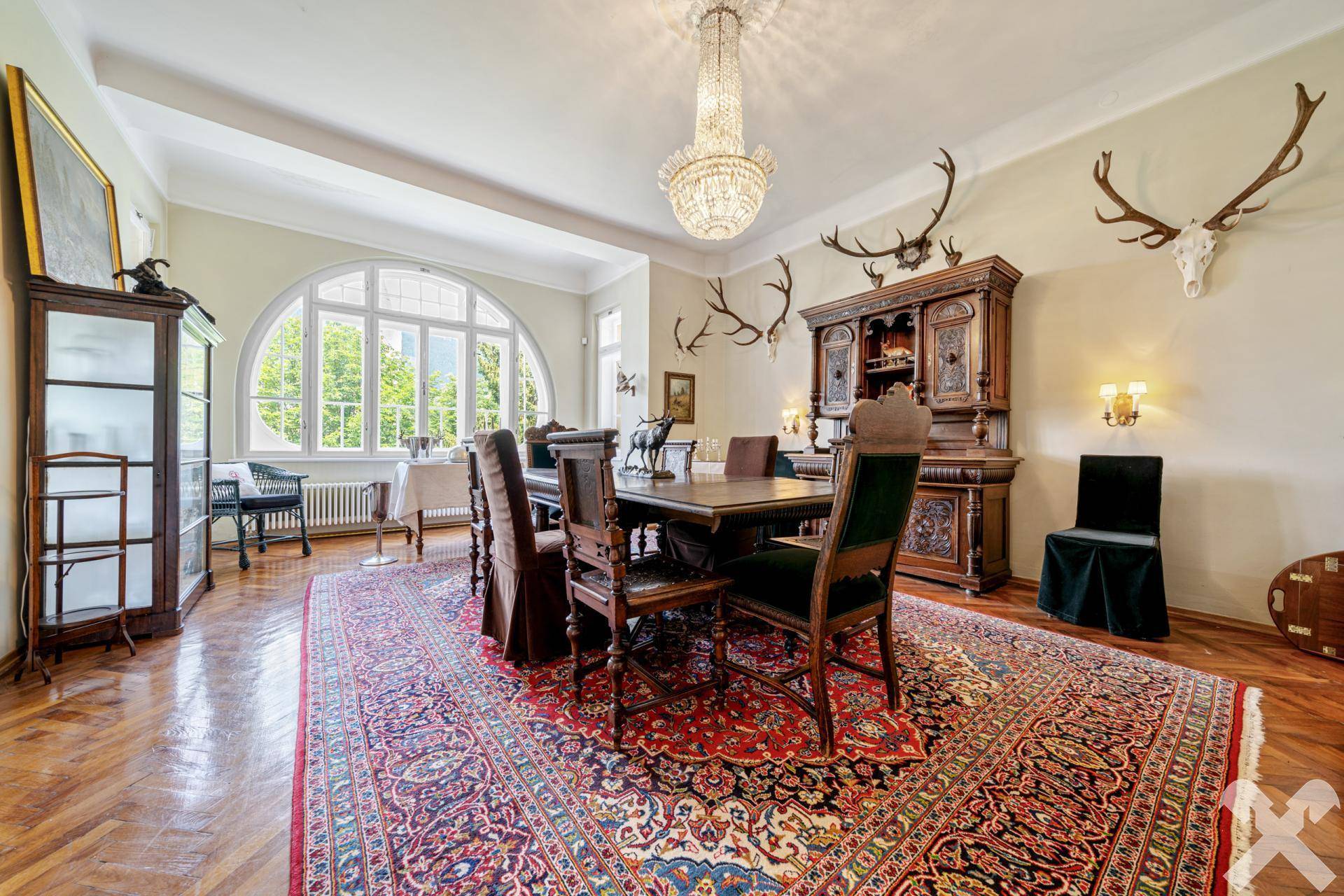Repräsentativer Speisesaal mit großem Holztisch, Jagdtrophäen und Bogenfenster.