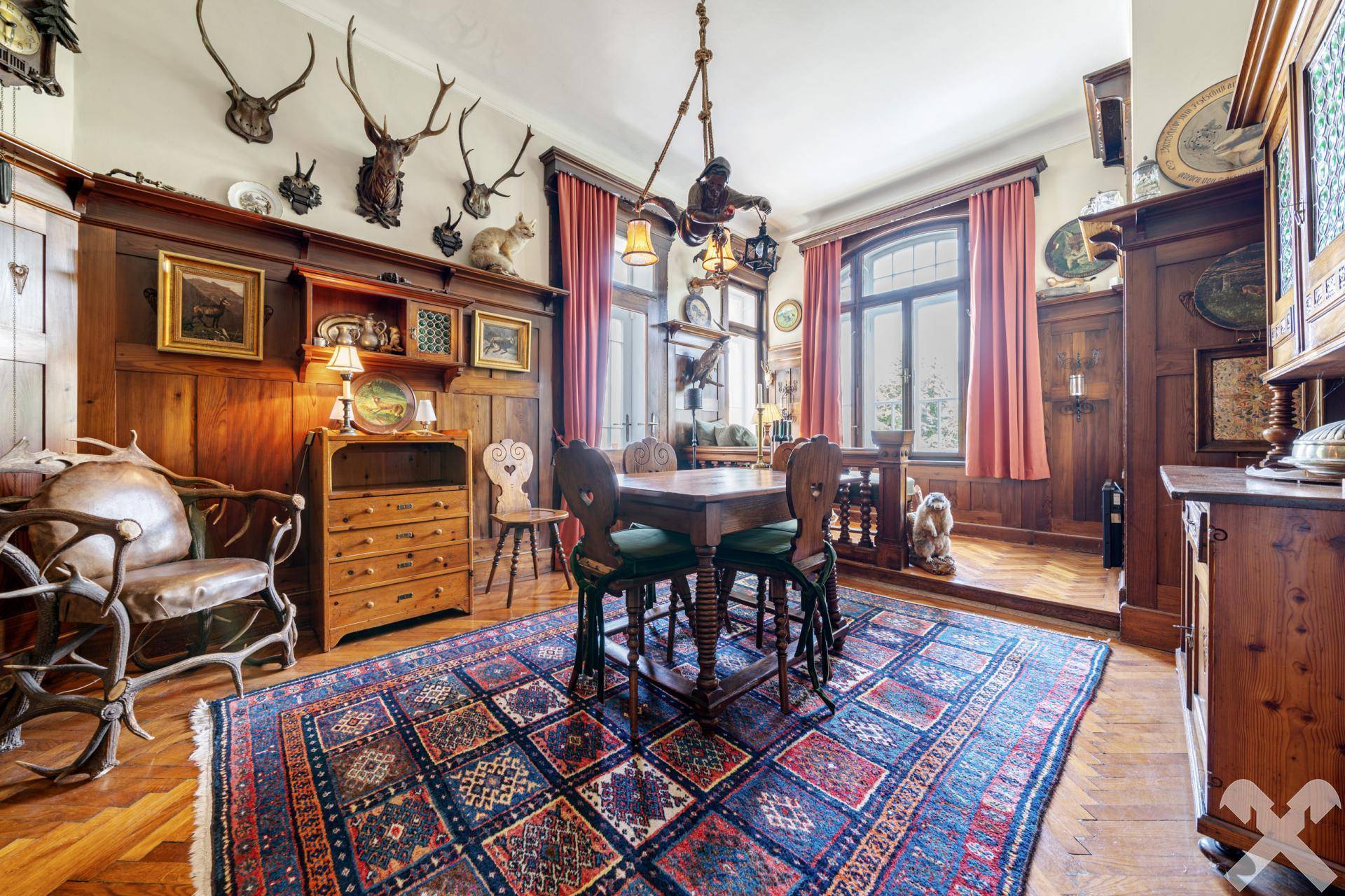 Traditioneller Essbereich mit Holztäfelung, Jagdtrophäen und orientalischem Teppich.