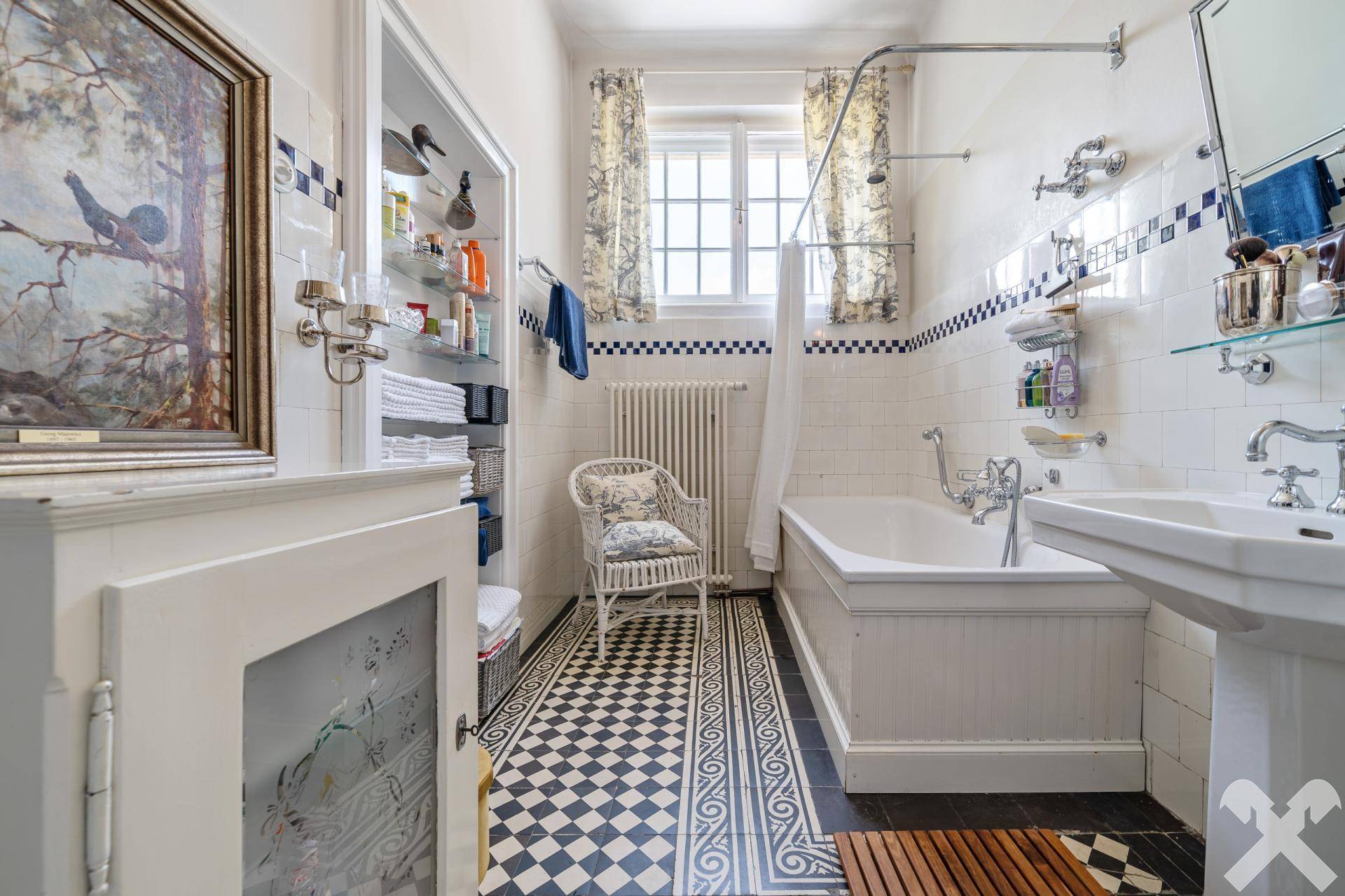 Klassisches Badezimmer mit Badewanne, Waschbecken und Schachbrettmuster-Fliesen am Boden.