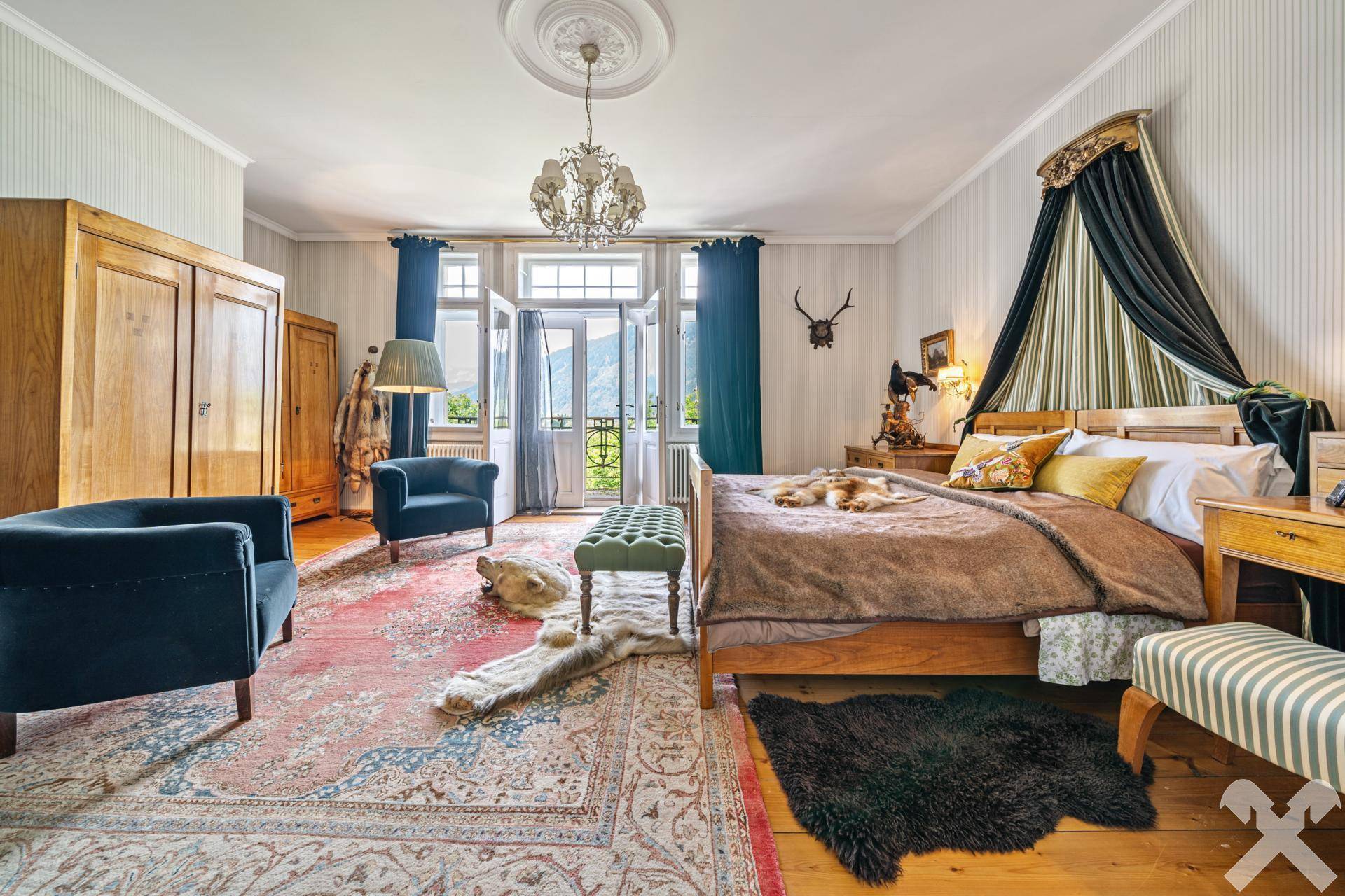 Geräumiges Schlafzimmer mit Himmelbett, Holzboden und Zugang zum Balkon mit Bergblick.