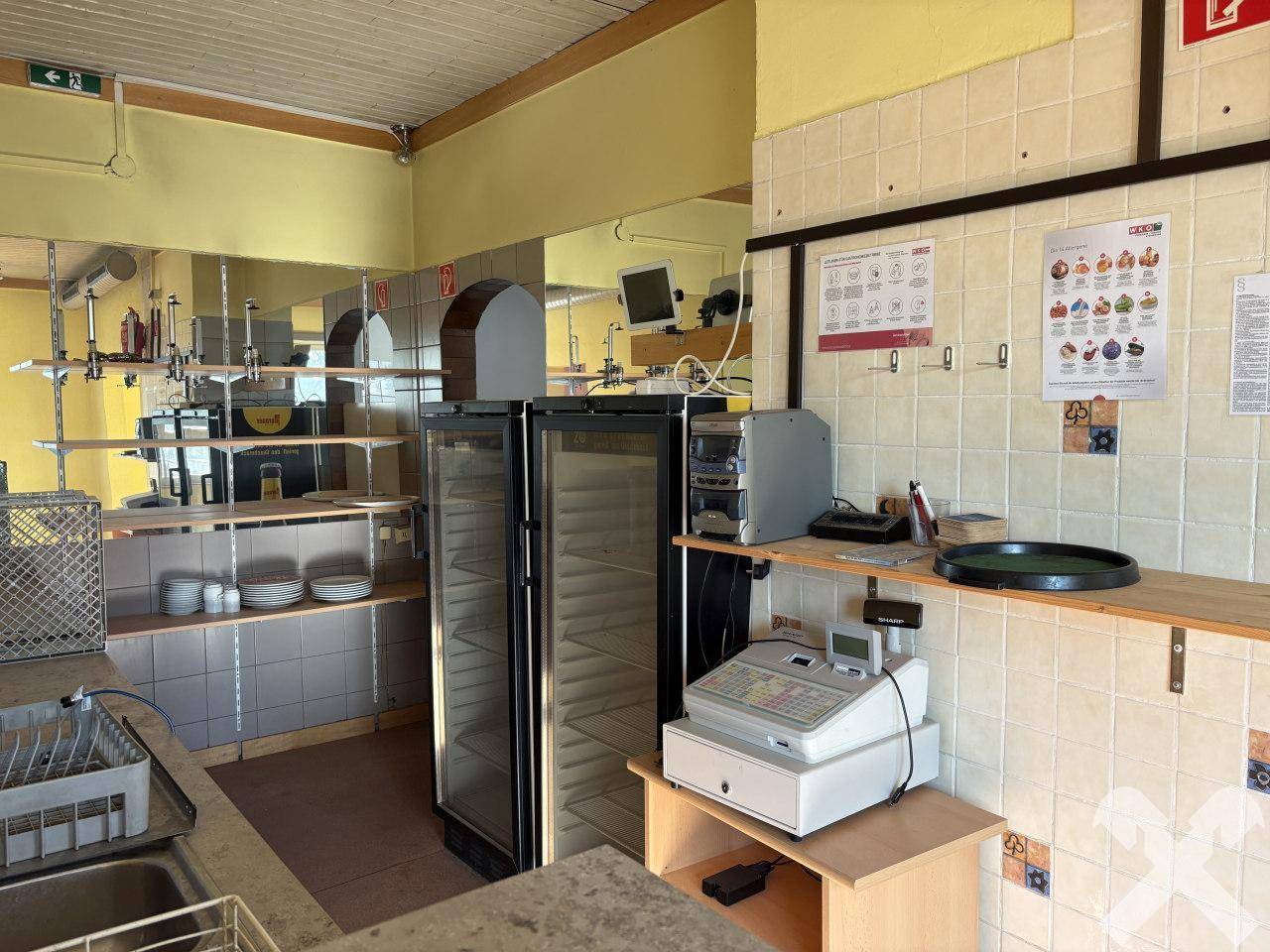 Kommerzielle Küchenzeile mit Fliesenwänden, Spülbecken und Kühlgeräten für den Gastronomiebetrieb.