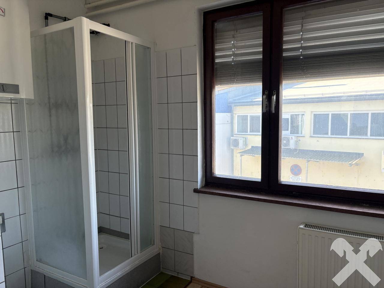 Badezimmer mit Duschkabine, Fliesenwänden und einem Fenster mit Blick nach draußen.