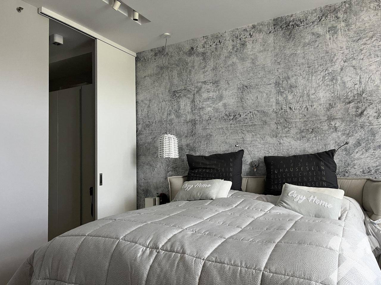Schlafzimmer mit großem Bett, dekorativer Wandgestaltung und Schiebetür.