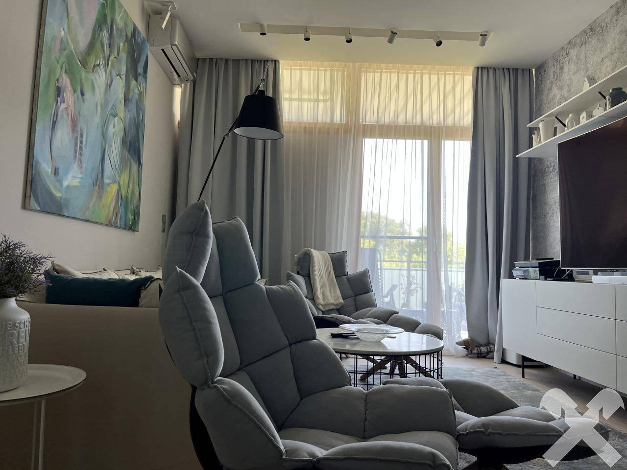 Helles Wohnzimmer mit großen Fenstern, die viel Tageslicht hereinlassen und einen Ausblick bieten.