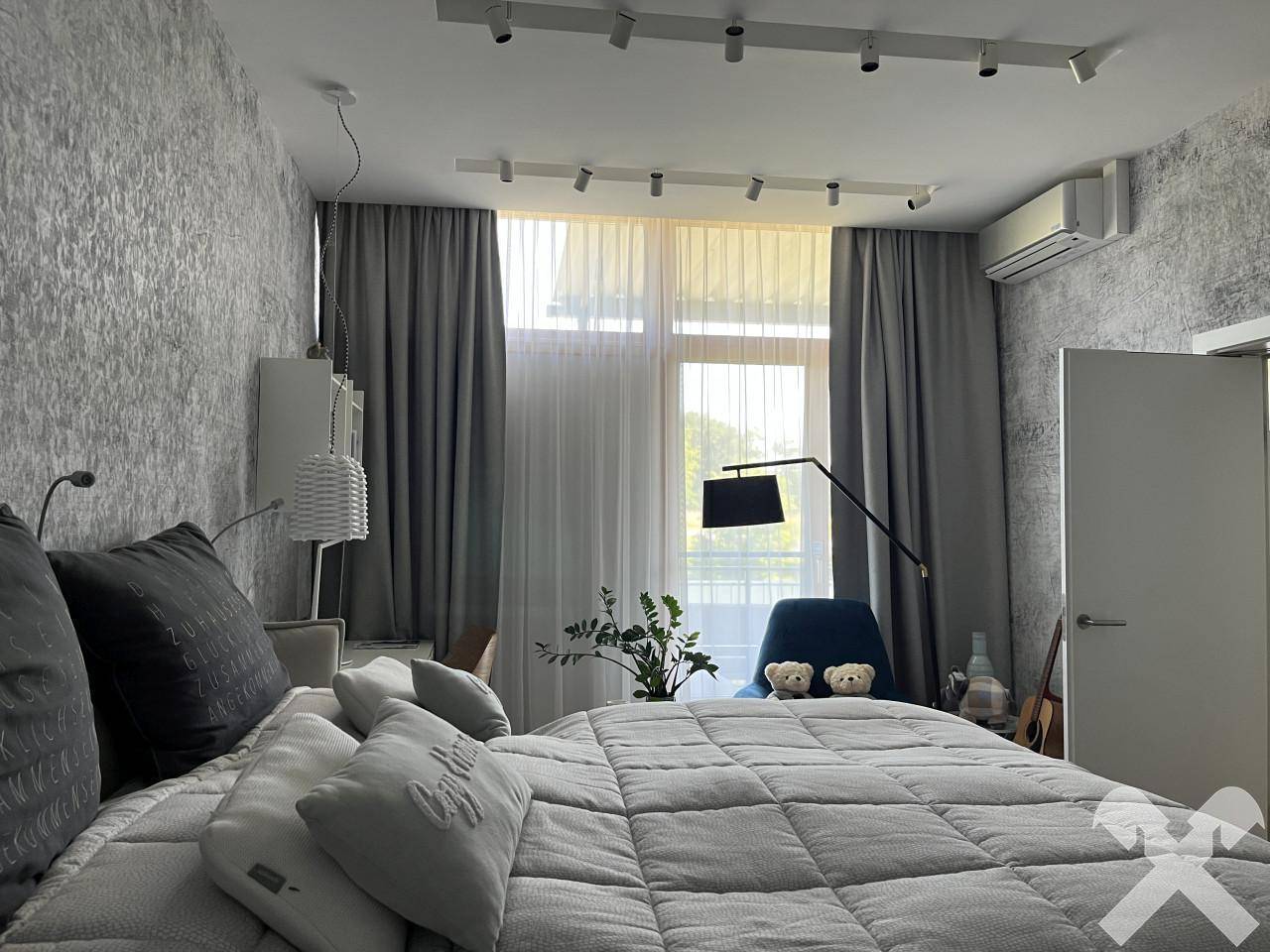 Modernes Schlafzimmer mit großem Bett, strukturierter Tapete und viel Tageslicht.