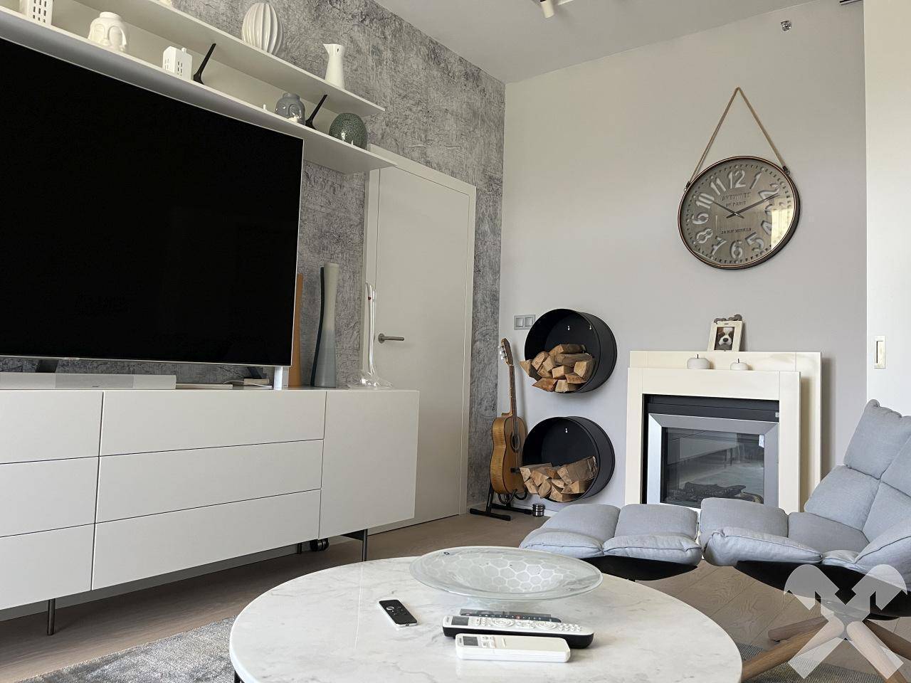 Wohnzimmer mit modernem Kamin, Fernseher und dekorativer Wandgestaltung.