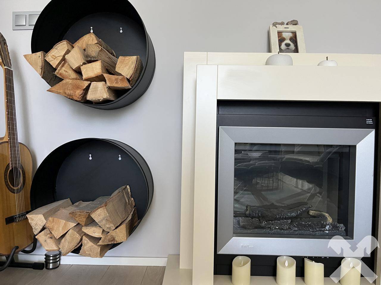 Detailansicht eines modernen Kamins mit Holzscheiten in dekorativen Haltern.