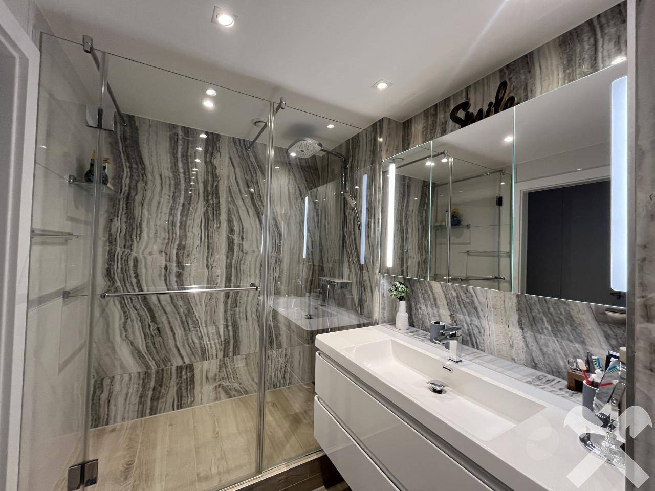 Modernes Badezimmer mit großer begehbarer Dusche und eleganten Marmorfliesen.