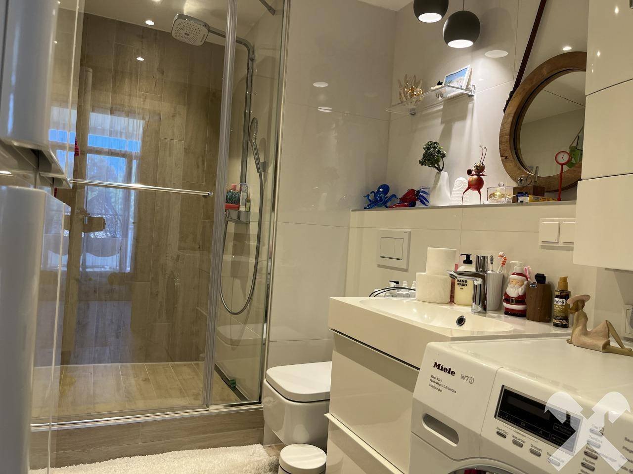 Modernes Badezimmer mit Dusche, Waschmaschine und runden Spiegeln.