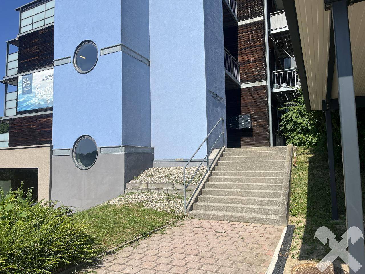 Außenansicht eines modernen Gebäudes mit blauer Fassade und runden Fenstern.