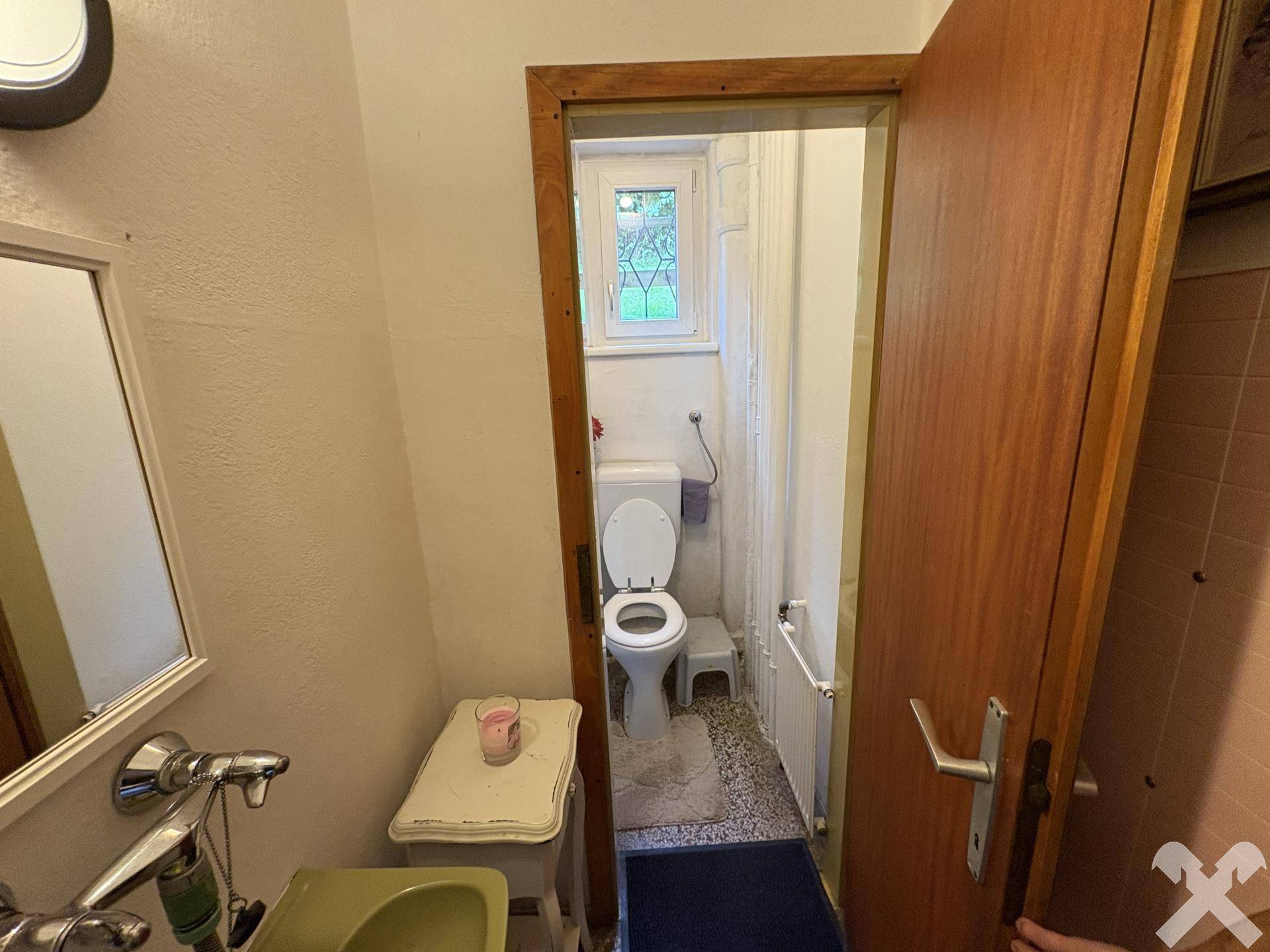 Kleines WC mit Fenster, einfacher Ausstattung und Fliesenboden.