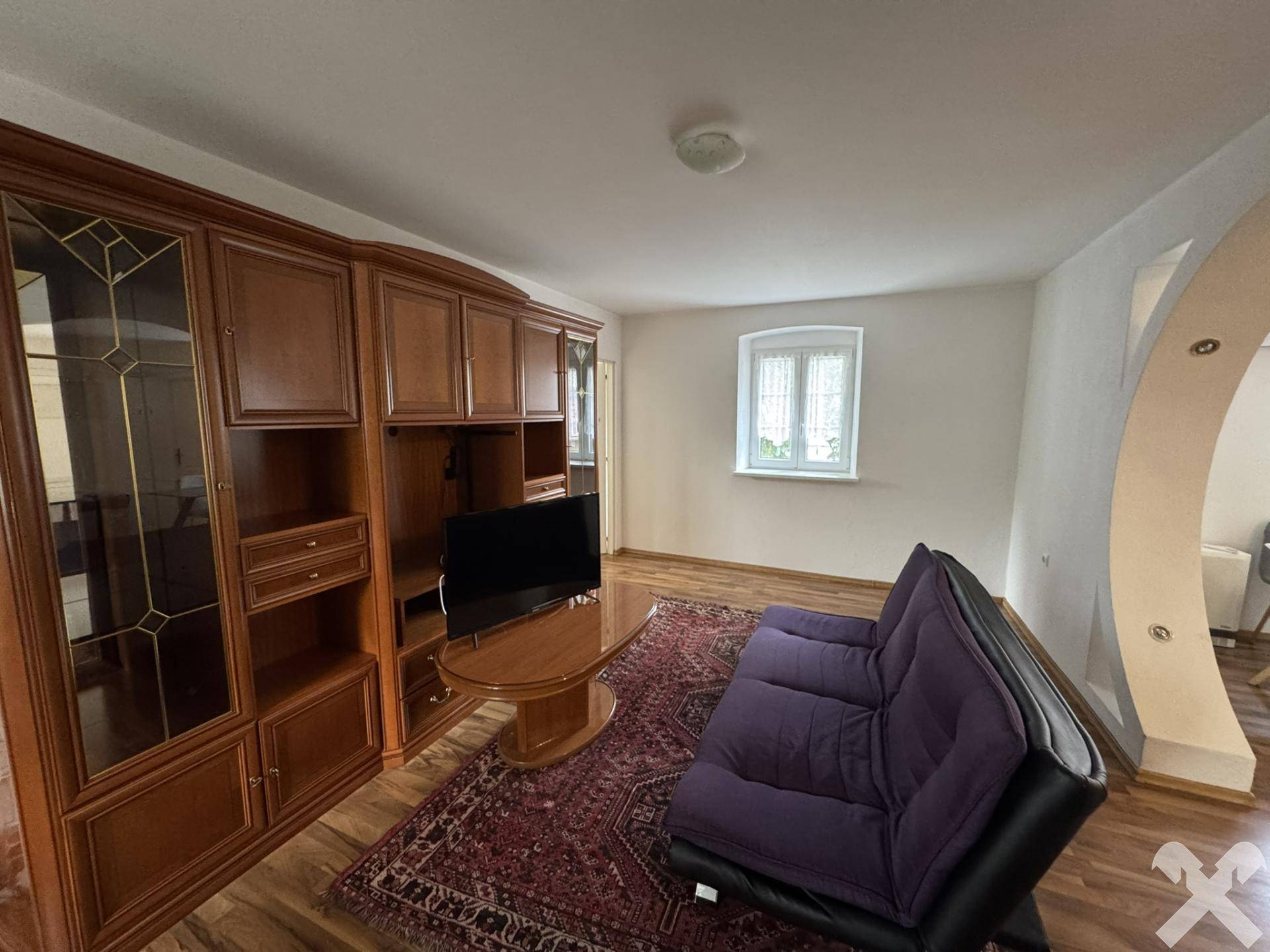 Gemütliches Wohnzimmer mit großem Holzschrank, Sofa und Teppichboden.