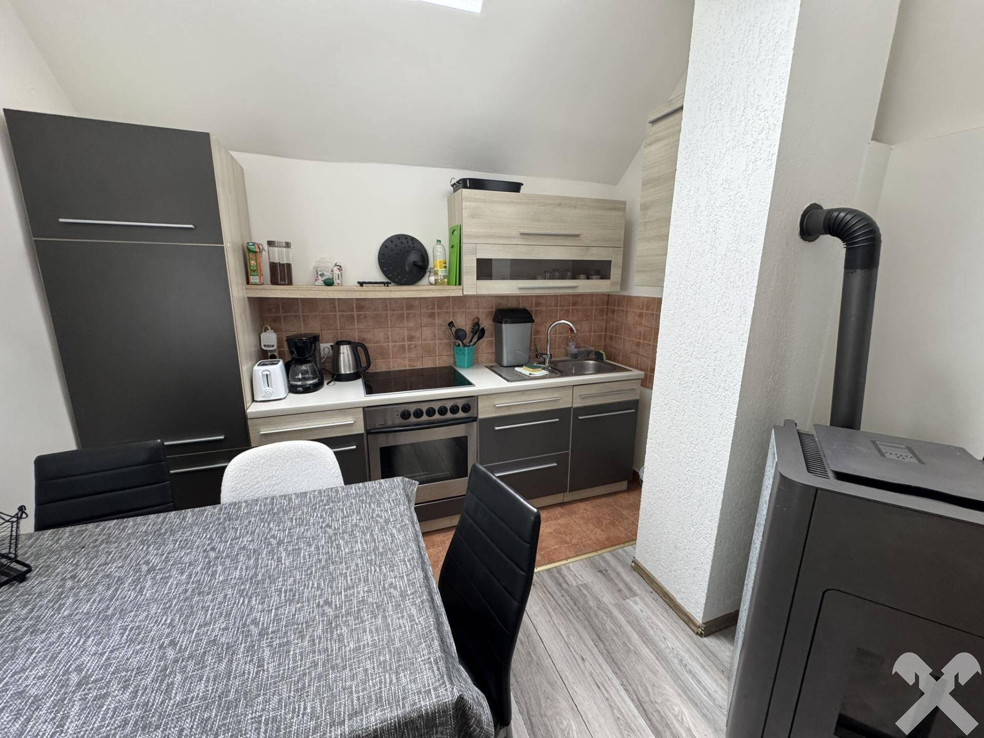 Küche mit Essbereich, Holzofen und modernen Schränken unter Dachschräge.