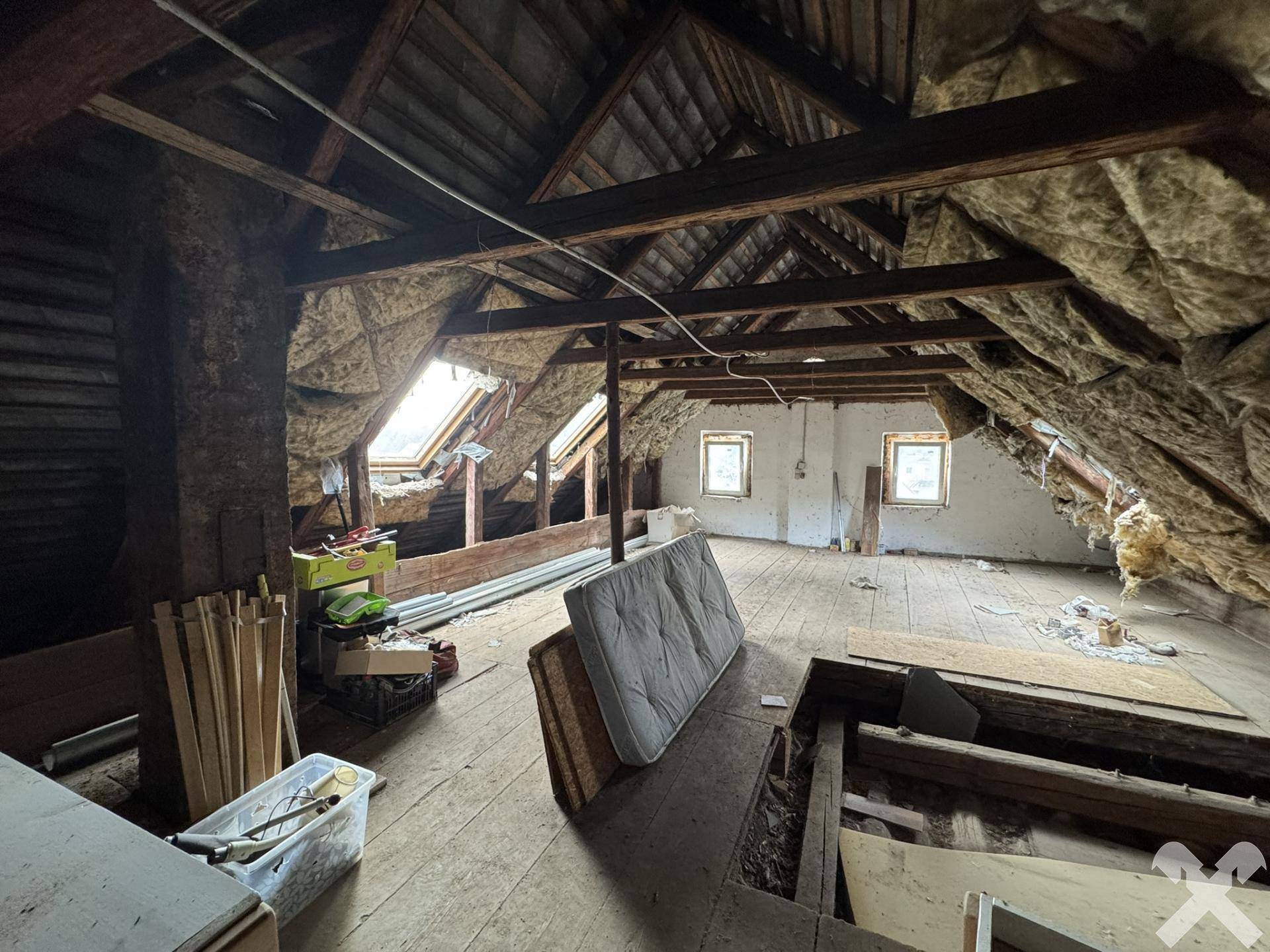 Geräumiger Dachboden mit sichtbaren Holzbalken und Dachfenstern, bereit für Ausbau.