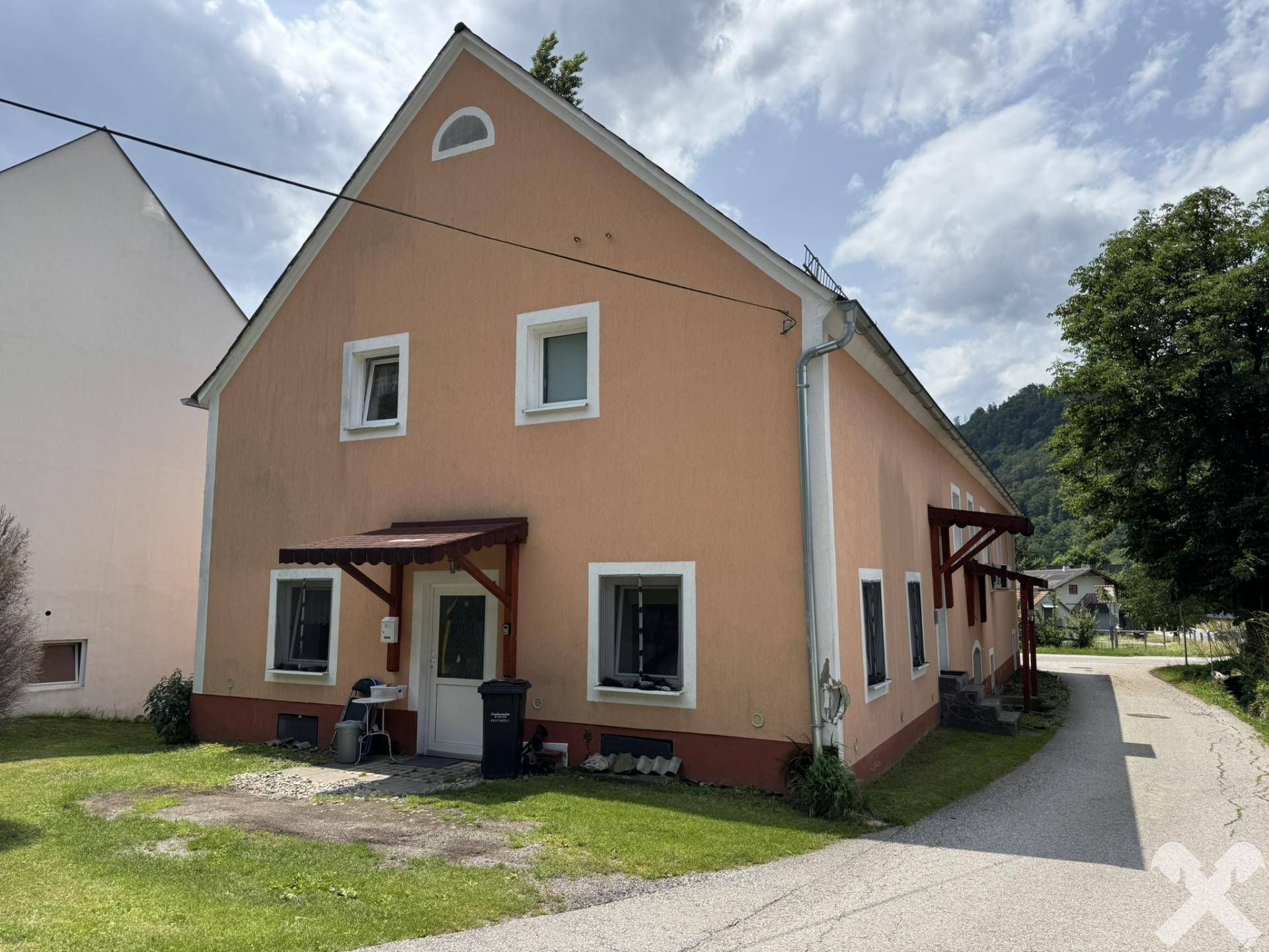 Seitenansicht des Wohnhauses mit Eingangsbereich und Vordach in ländlicher Umgebung.