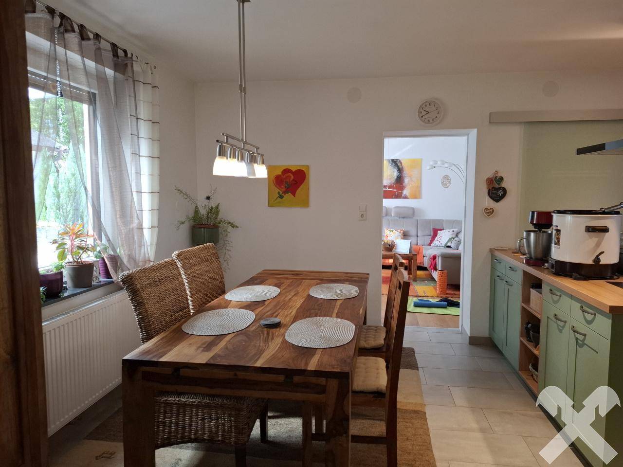 Heller Essbereich mit Holztisch und Blick in das angrenzende Wohnzimmer.