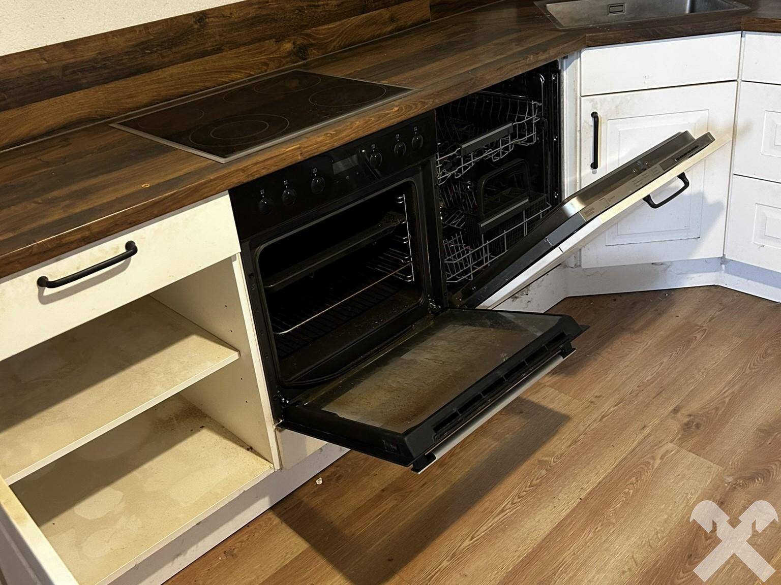 Küche mit Holzarbeitsplatte, integriertem Backofen und Geschirrspüler, die eine Auffrischung benötigt.