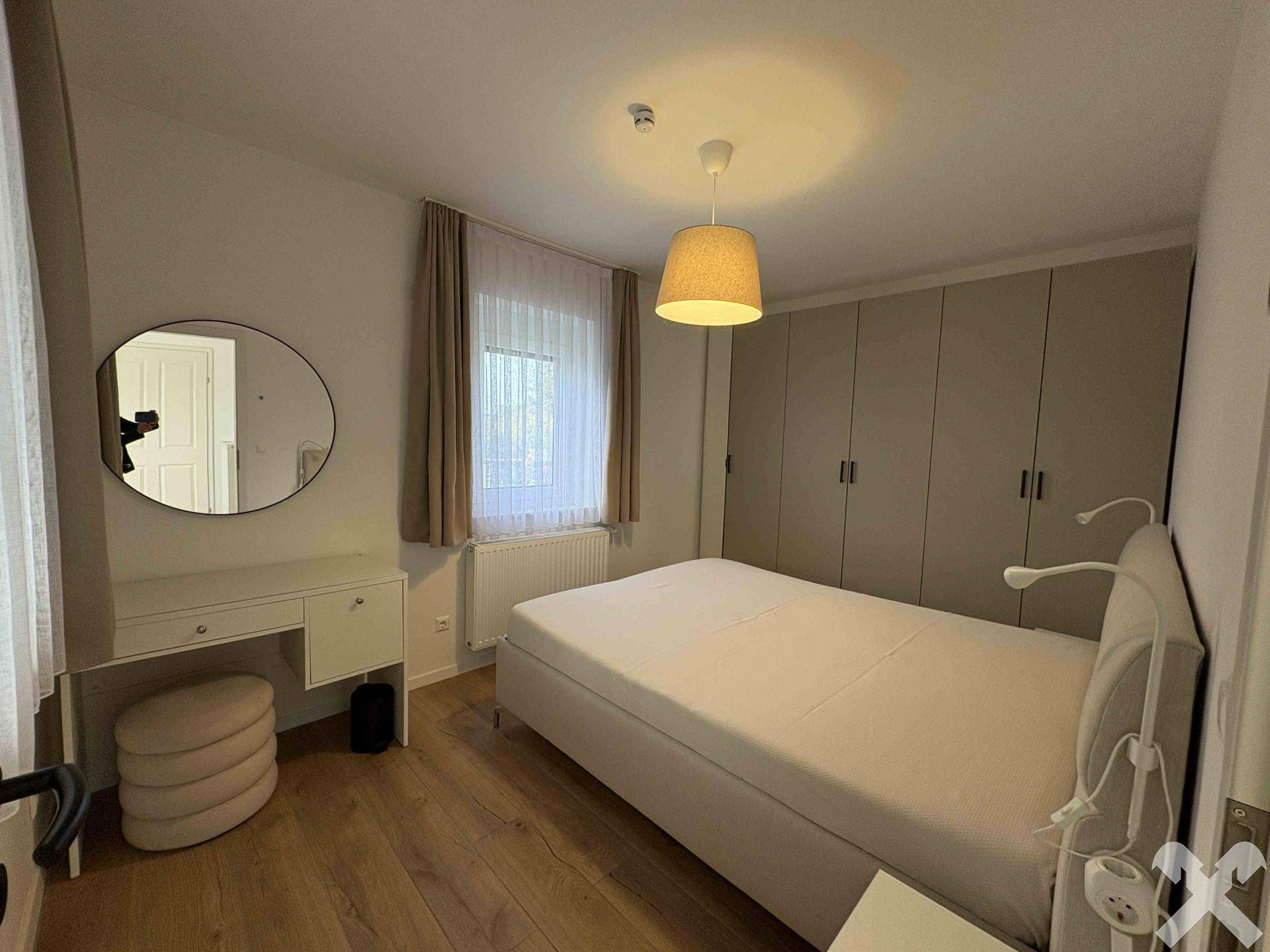 Helles Schlafzimmer mit Doppelbett, Einbauschränken und Holzboden.