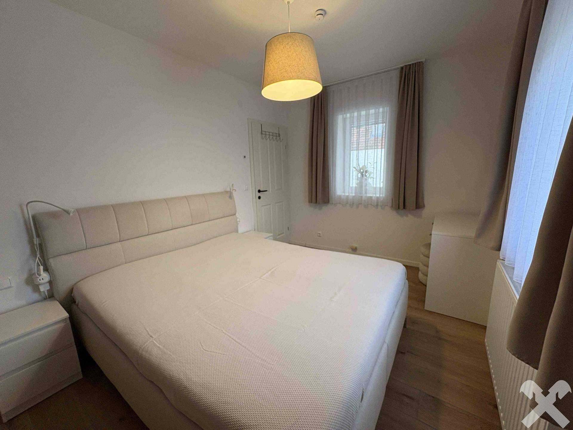 Gemütliches Schlafzimmer mit großem Bett, Nachttisch und Fenster für natürliches Licht.