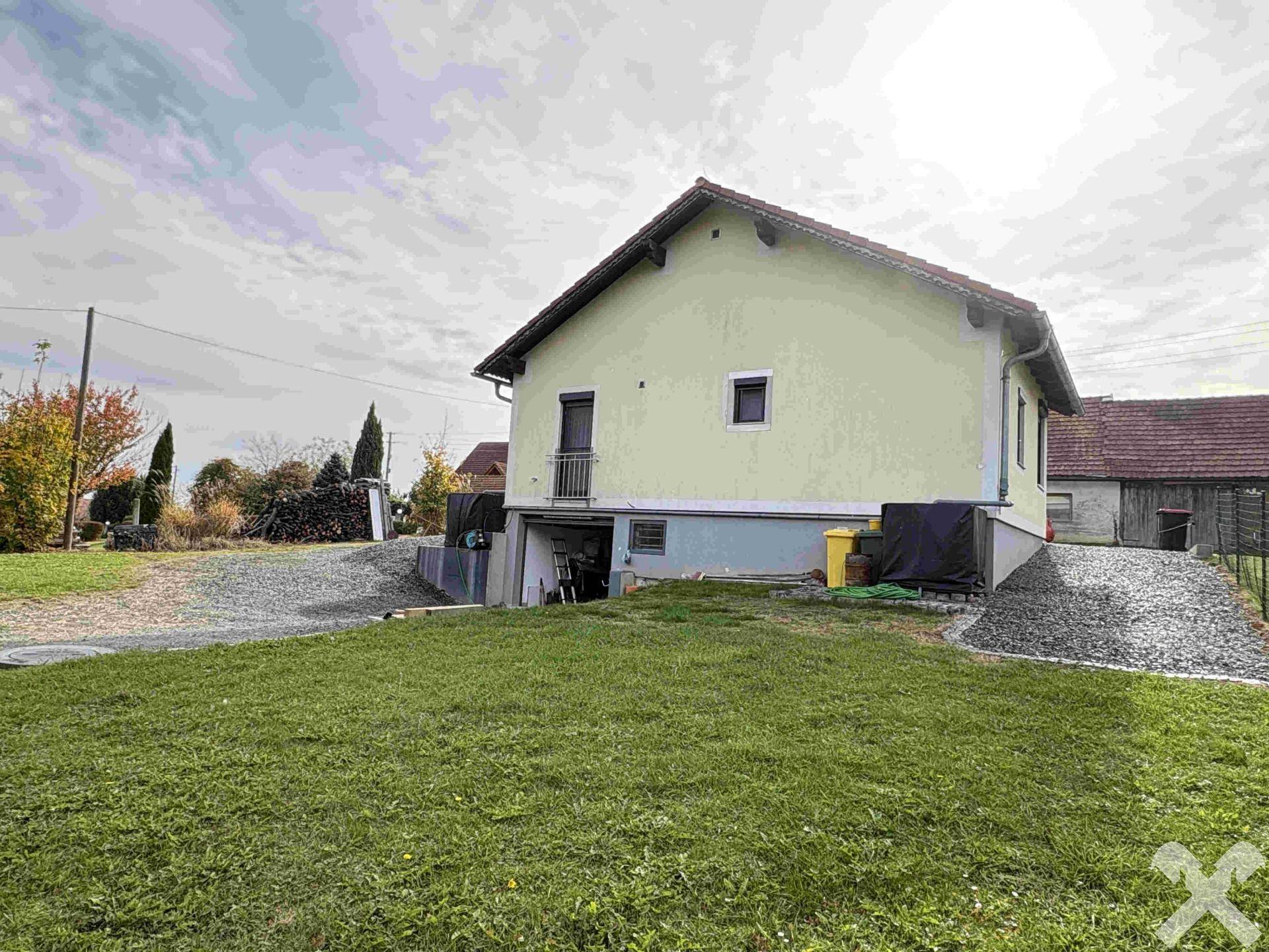 Rückseite des Hauses mit Rasenfläche, Kiesauffahrt und Zugang zum Untergeschoss.