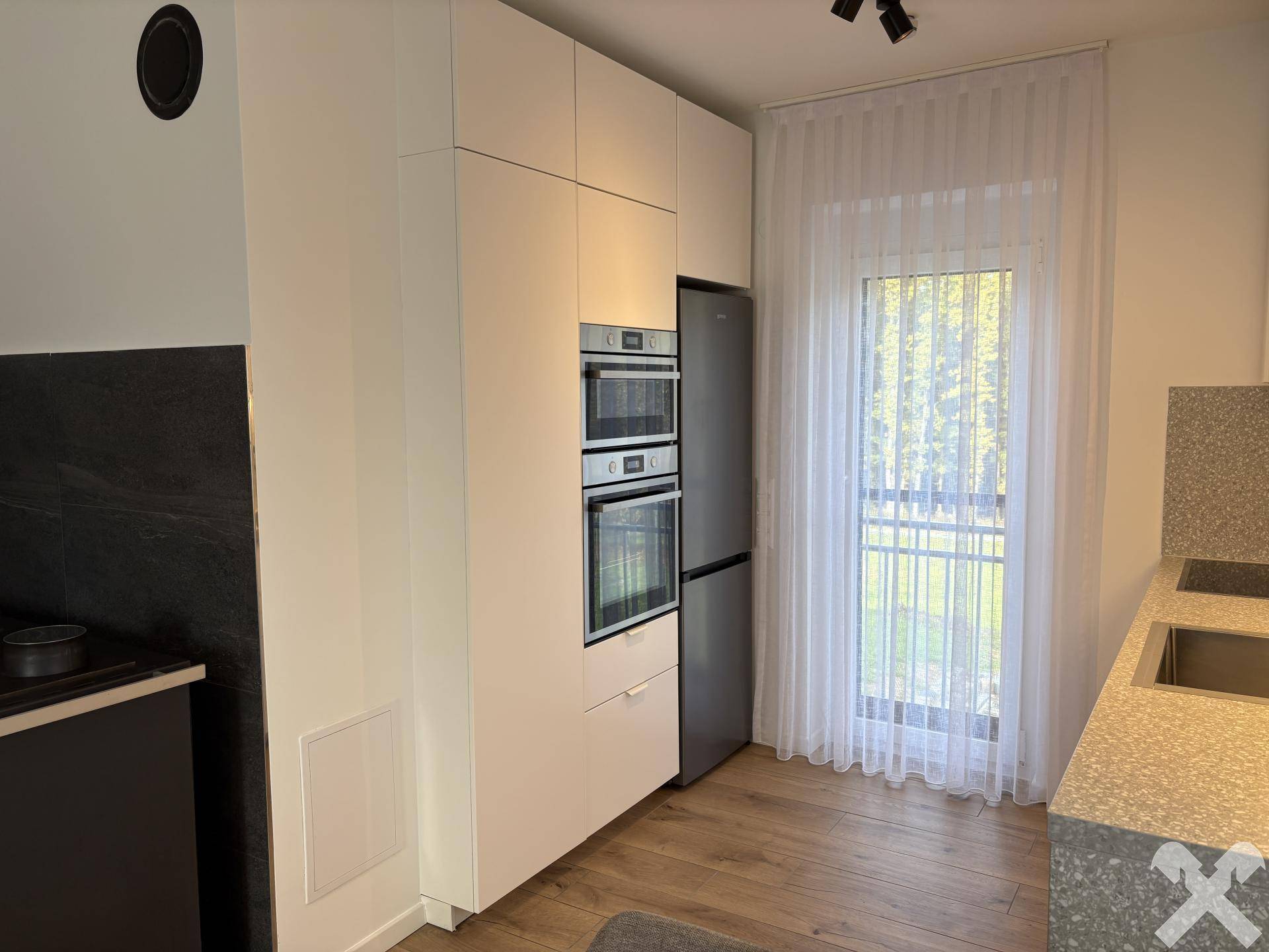 Moderne Einbauküche mit integrierten Geräten, Kühlschrank und Zugang zum Balkon.