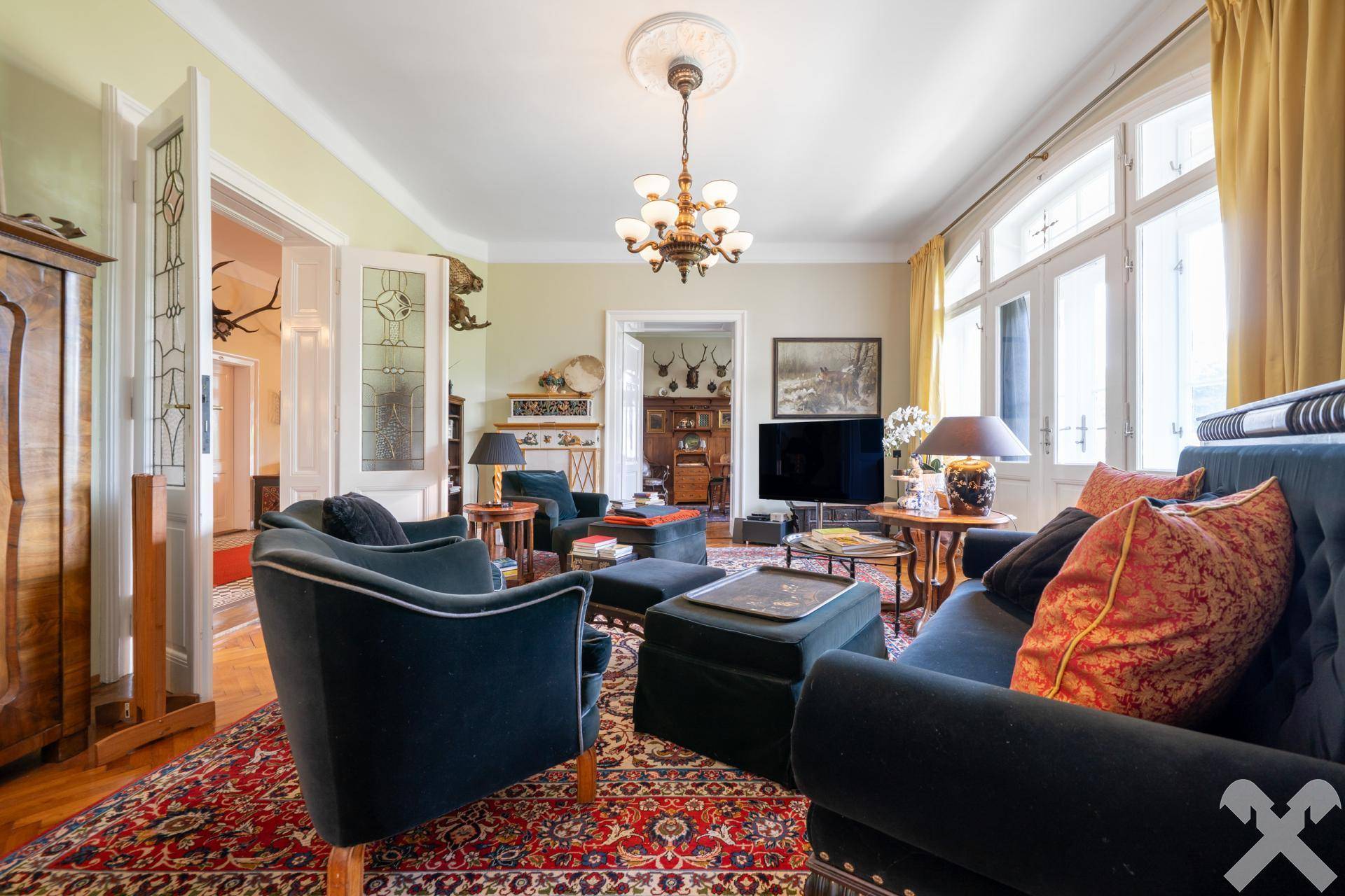 Elegantes Wohnzimmer mit blauen Samtsofas, orientalischem Teppich und hohen Fenstern.